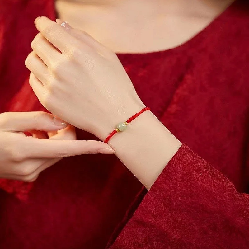 Red string and jade bracelet worn on a woman's wrist